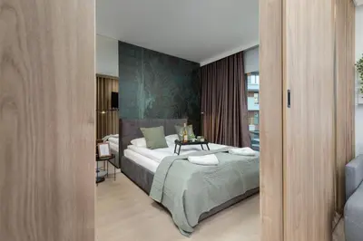 a white bedroom with a bed and two lamps at Wiślane Tarasy Lux Apartments Cracow by Renters Prestige in Kraków