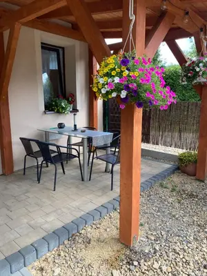 a patio with a table and chairs and flowers at Dom Wakacyjny Gajówka z ogrodem i jacuzzi do stoku 2km in Rzyki