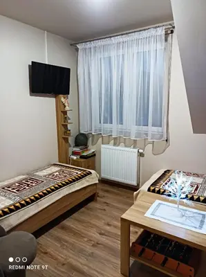 two beds in a room with a window and a table at Dom Wakacyjny Gajówka z ogrodem i jacuzzi do stoku 2km in Rzyki