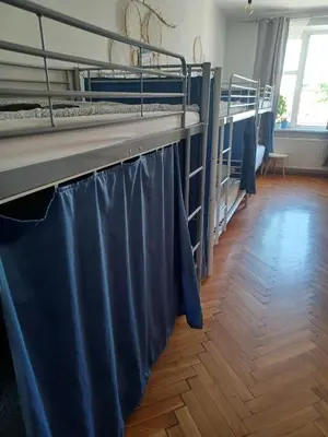 a room with two bunk beds with blue curtains at REAL Hostel in Kraków