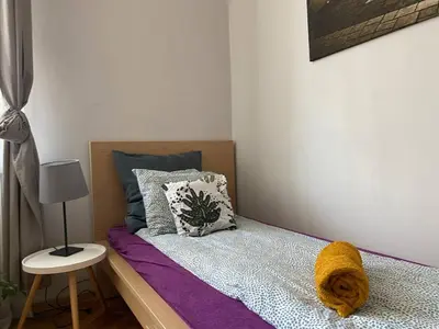 a small bedroom with a bed with purple sheets at REAL Hostel in Kraków