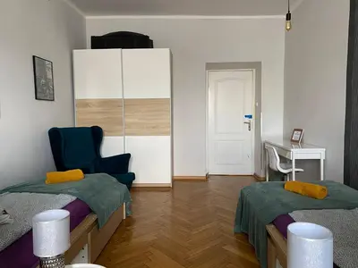 a room with two beds and a chair and a desk at REAL Hostel in Kraków