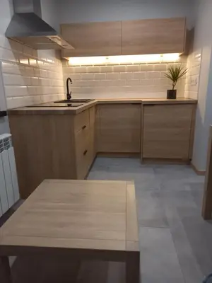 a kitchen with wooden cabinets and a sink and a table at Apartament na Słonecznej in Łączany