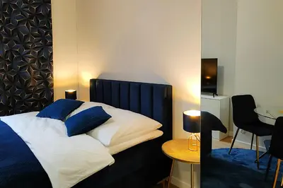 a bedroom with a bed with blue pillows and a table at Hugo Star Apartments in Kraków