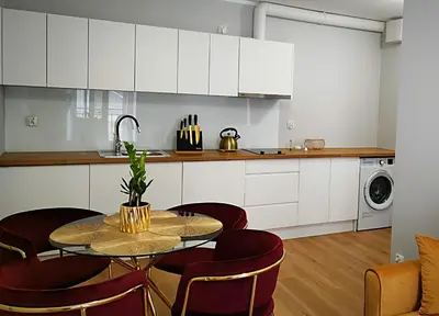 a kitchen with white cabinets and a table and chairs at Hugo Star Apartments in Kraków