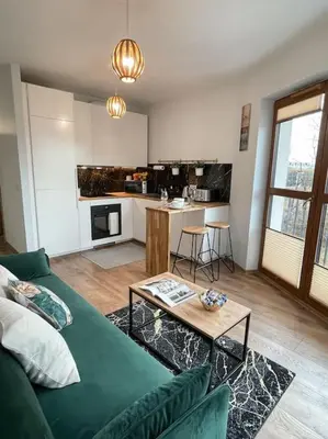 a living room with a green couch and a kitchen at New One Bedroom Apartment with balcony in Kraków