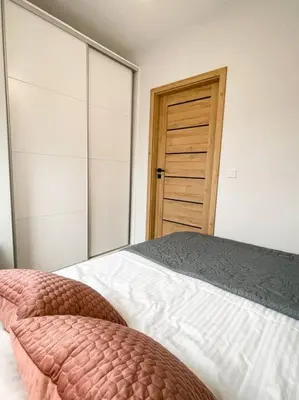 a bedroom with a bed and a wooden door at New One Bedroom Apartment with balcony in Kraków