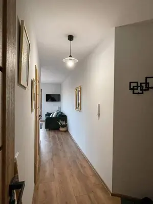 a hallway with white walls and a hard wood floor at New One Bedroom Apartment with balcony in Kraków