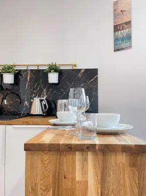 a wooden table with wine glasses and plates on it at New One Bedroom Apartment with balcony in Kraków