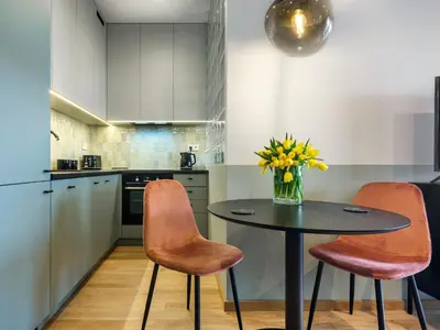 a kitchen with a table with chairs and a vase of flowers at Wislane Tarasy II by Tyzenhauz in Kraków