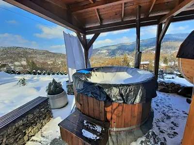 a hot tub on a deck with snow on the ground at Chata Panorama in Stróża