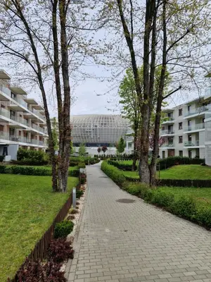 a walkway in a park with trees and a building at Apartament ulica Lema - Tauron Arena Kraków, parking, WiFi in Kraków