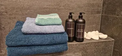 two bottles on a shelf in a bathroom with towels at Apartament ulica Lema - Tauron Arena Kraków, parking, WiFi in Kraków
