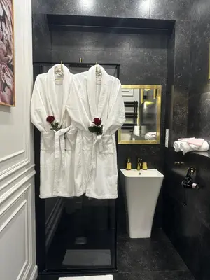 a bathroom with white robes hanging on a wall at Apartament z Jacuzzi Kraków GLAMOUR Starowiślna in Kraków