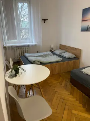 a small room with two beds and a table and chairs at Classy Rooms in Old Town in Kraków