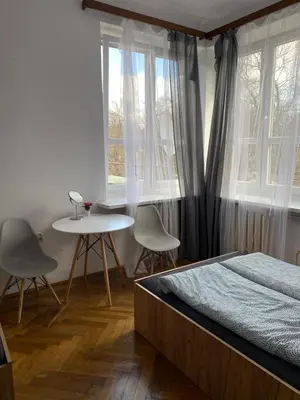 a bedroom with a bed and a table and windows at Classy Rooms in Old Town in Kraków