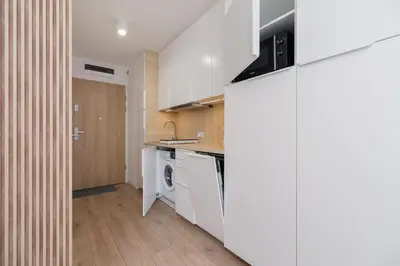 a kitchen with white cabinets and a washer and dryer at Saska Blu Studios Premium by Noclegi Renters in Kraków