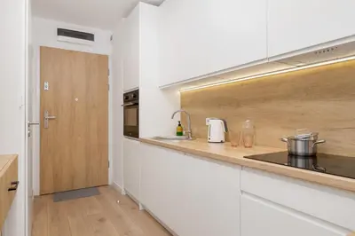 a kitchen with white cabinets and a wooden counter top at Saska Blu Studios Premium by Noclegi Renters in Kraków