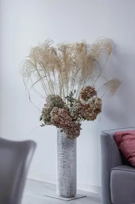 a vase filled with dried flowers in a living room at Business Apartment for Home Office Kołaczy Kraków by Noclegi Renters in Kraków