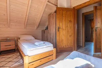 a bedroom with two beds in a wooden cabin at Domki Gorczański Zakątek - Jacuzzi in Nowy Targ