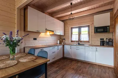 a kitchen with white cabinets and a wooden floor at Domki Gorczański Zakątek - Jacuzzi in Nowy Targ