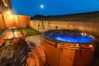 a large hot tub in a backyard with a table at Domki Gorczański Zakątek - Jacuzzi in Nowy Targ