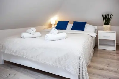 a bedroom with two beds with white sheets and blue pillows at Aleja 69 in Kraków