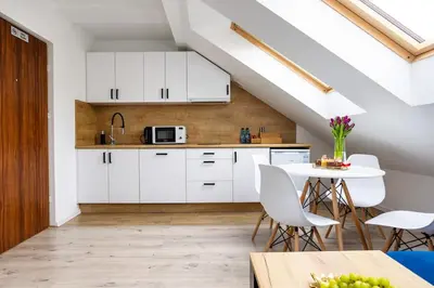 a kitchen with white cabinets and a table at Aleja 69 in Kraków