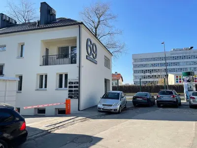a white building with cars parked in a parking lot at Aleja 69 in Kraków