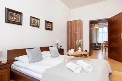 a bedroom with two beds with white sheets and a table at Przytulnie i naturalnie — Balkon in Kraków