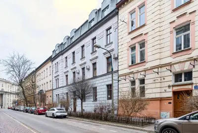 a large white building with cars parked on a street at Przytulnie i naturalnie — Balkon in Kraków