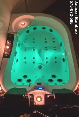 a bathtub with a green table in a room at Jacuzzi Kraków Bamboo in Kraków