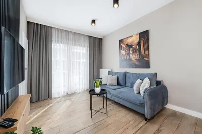 a living room with a blue couch and a tv at Krakowiak Apartment in Kraków