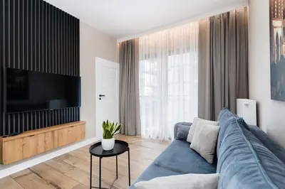a living room with a blue couch and a tv at Krakowiak Apartment in Kraków