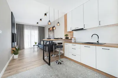 a kitchen with white cabinets and a table with chairs at Krakowiak Apartment in Kraków