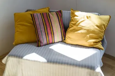 a couch with three pillows and a white envelope at Sekretne gniazdko w tajemniczym ogrodzie in Kraków