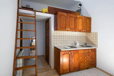 a kitchen with wooden cabinets and a ladder at Sekretne gniazdko w tajemniczym ogrodzie in Kraków