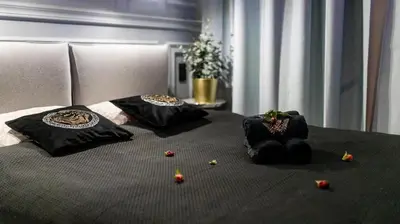 a bed with black pillows and flowers on it at Glamour Jacuzzi Apartment in Kraków