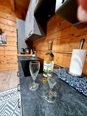 a bottle of wine and two wine glasses on a counter at Gorczańska Chata z tarasem widokowym in Poręba Wielka