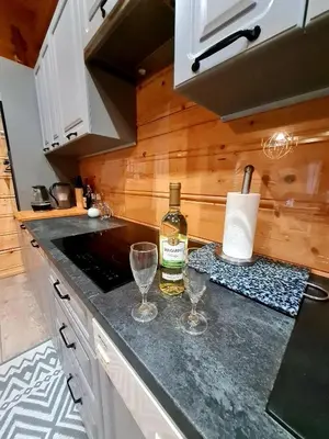 a kitchen with a bottle of wine and two glasses on a counter at Gorczańska Chata z tarasem widokowym in Poręba Wielka