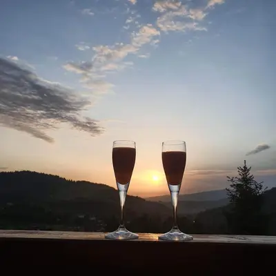 two glasses of wine sitting on a table with the sunset at Gorczańska Chata z tarasem widokowym in Poręba Wielka