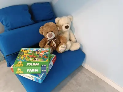 two teddy bears sitting on a blue couch with books at Apartament Kristel Zator in Podolsze