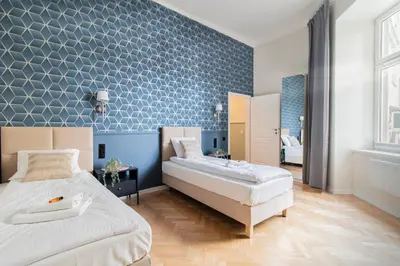 a bedroom with two beds and a blue wall at Modern Apartments Piłsudskiego Street in Kraków