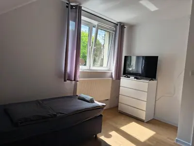 a bedroom with a bed and a tv and a window at Pokoje Kraków Tyniec Hostel in Kraków