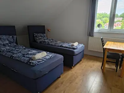a living room with two beds and a table and a chair at Pokoje Kraków Tyniec Hostel in Kraków