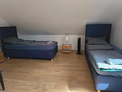 two beds in a room with a wooden floor at Pokoje Kraków Tyniec Hostel in Kraków