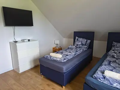 two blue beds in a room with a tv at Pokoje Kraków Tyniec Hostel in Kraków