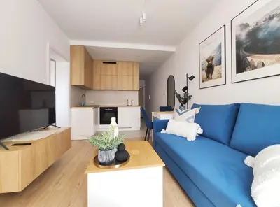 a living room with a blue couch and a kitchen at Mogilska 120D by Homeprime in Kraków