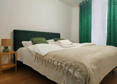 a bedroom with a large bed with green curtains at Hugo Eden Apartments in Kraków