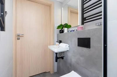 a bathroom with a sink and a door at Śródmieście Kątowa Air-conditioned Studio Kraków by Noclegi Renters in Kraków